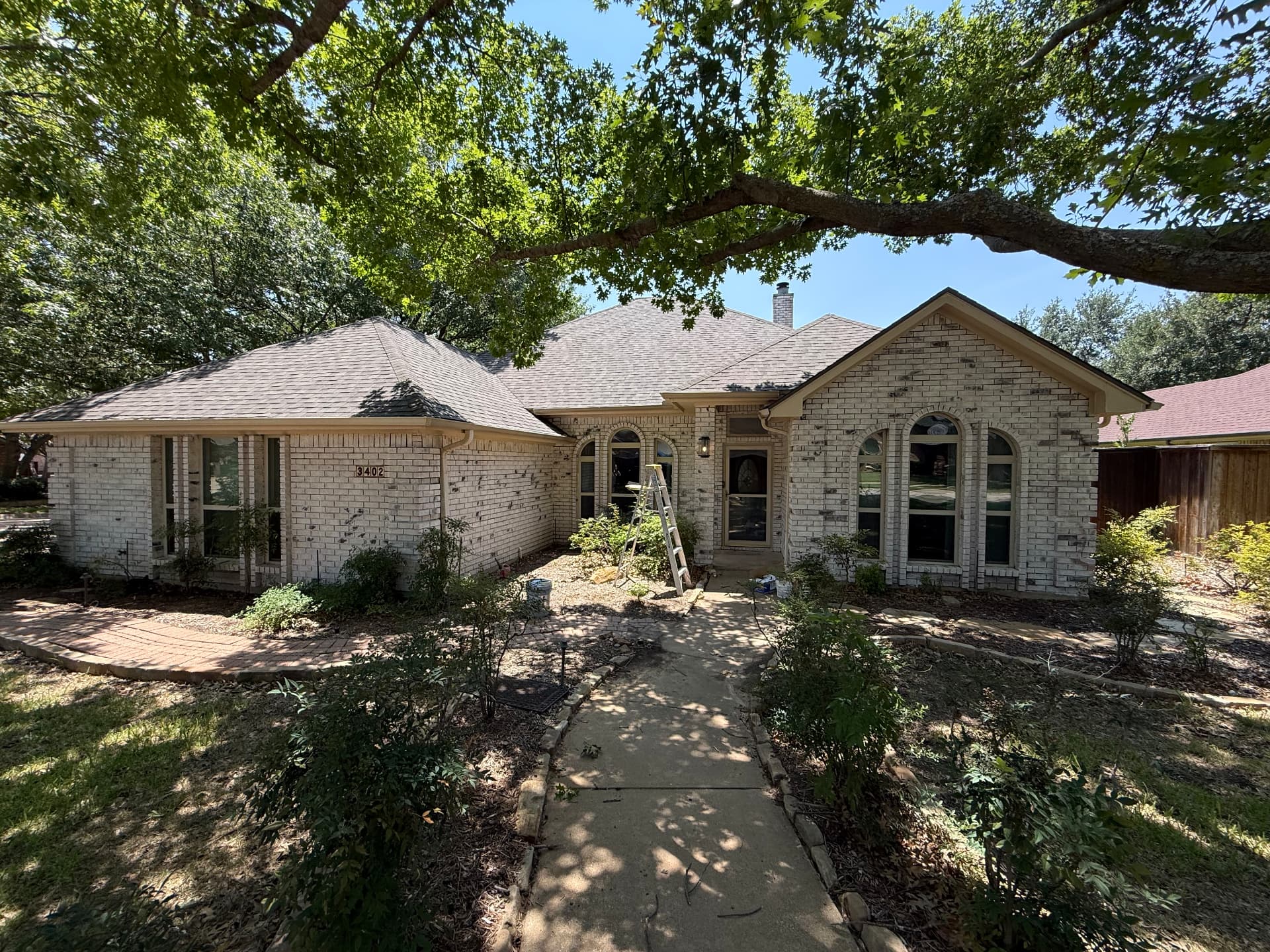 Brick home front elevation with faded cream trim and fascia before repaint