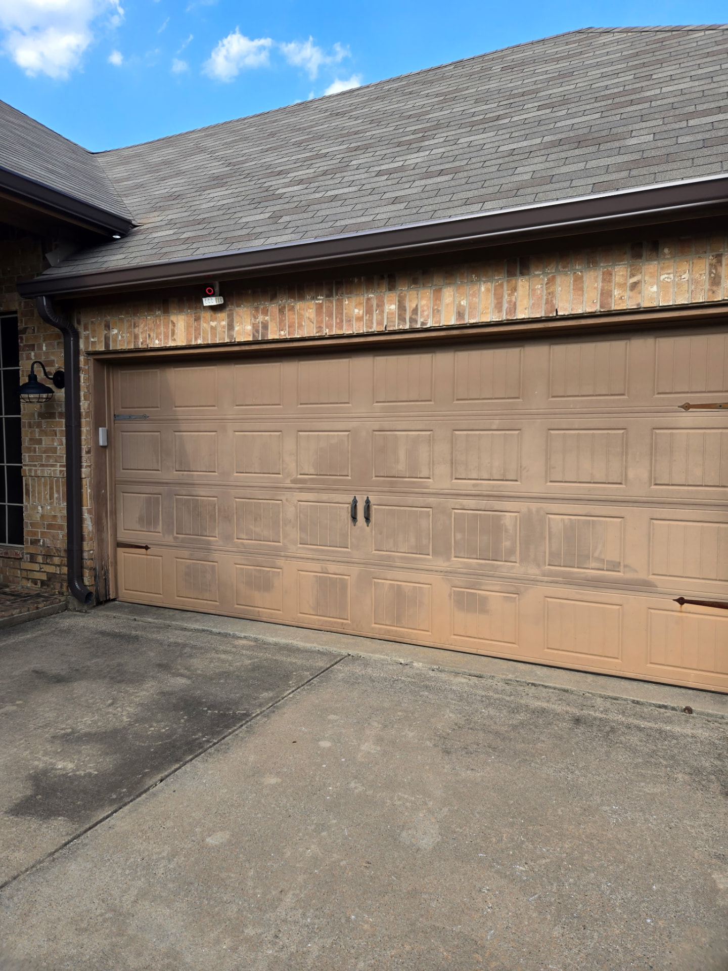 Faded and weathered tan garage door with streaking